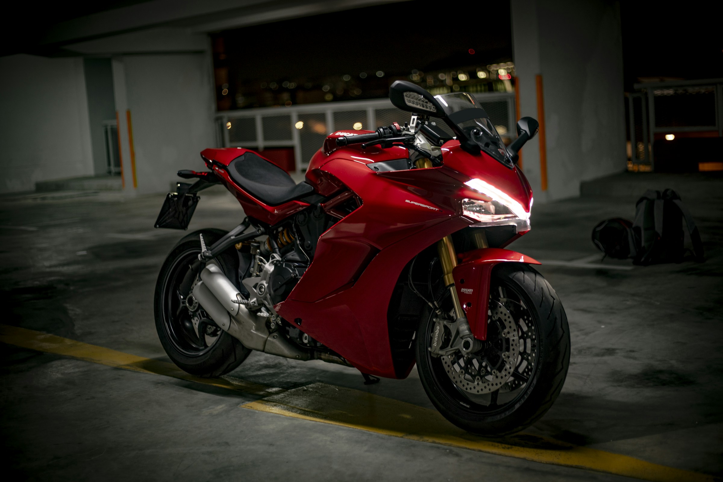 Ducati SuperSport vermelha em uma garagem, com o farol aceso
